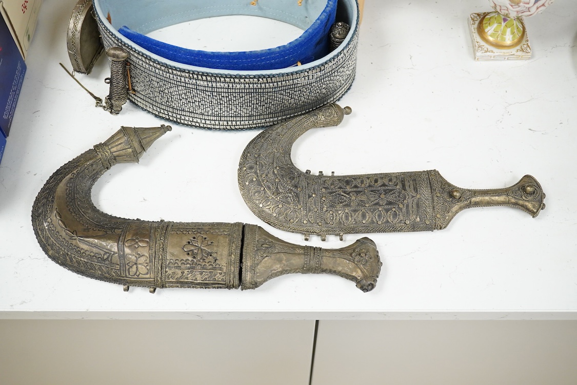 Two Yemeni white metal daggers white and two belts, largest dagger 31cm long